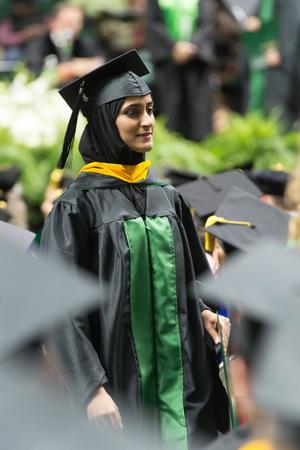 Primary view of object titled '[Graduate Student Walking with her Diploma]'.