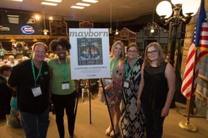 Primary view of object titled '[Mayborn Magazine team standing by poster of cover-page]'.