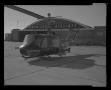 Photograph: [Photograph of a UH-1B Iroquois helicopter parked outside an American…