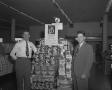Photograph: [Two Men Posing with a Store Display]