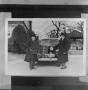 Photograph: [Two men standing in front of a car]