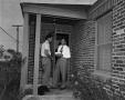 Photograph: [Two men on porch outside house]