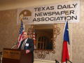 Photograph: [Bill Hartman standing at podium giving speech at TDNA meeting]