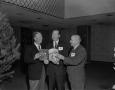 Photograph: [Roy Bacus and two men hold a magazine]