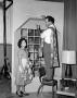 Primary view of [Melvin Dacus and a woman hanging curtains]