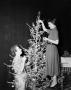 Photograph: [Photograph of Ann Alden and guest by Christmas tree]
