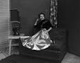 Photograph: [Photograph of Ann Alden seated on a patterned couch]