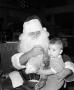 Photograph: [Photograph of Santa holding a baby at a KXAS Christmas Children's Ho…