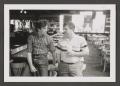 Photograph: [Photograph of Byrd Williams IV and a man talking in a bar]