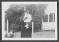 Primary view of [Photograph of a woman holding a baby outside]