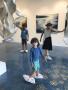 Photograph: [Children wearing face masks and shoe coverings in an art gallery]