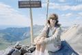 Photograph: [Carol sitting next to the Engineer Mountain sign]