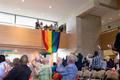 Photograph: [Unfurling pride flag at LGBTQ reception, from below]