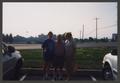 Photograph: [Two women and a man in a parking lot]