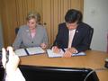 Photograph: [Gretchen Bataille and man sign papers at Thailand delegation meeting…