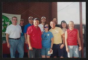 Primary view of object titled '[11 people posed by a KDL 106.7 radio station banner: Lone Star Ride 2003 event photo]'.
