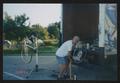 Photograph: [Man pumping a bicycle tire by an open loading truck: Lone Star Ride …