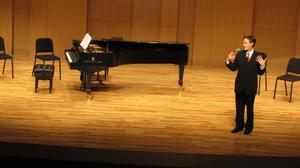 Primary view of object titled '[Heggie standing next to piano, Student recital during Jake Heggie's residency, 2]'.