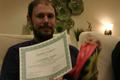 Photograph: [Zachary Austrew poses with joke certificate]