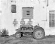 Photograph: [A tractor parked in front of a building]