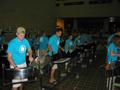 Primary view of [Rows of drummers in blue shirts performing for a crowd, 1]