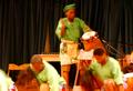Photograph: [A row of men dancing while two men play drums]