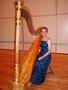 Photograph: [A woman in a blue dress sitting behind a harp]