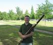 Photograph: [A man in a green shirt posing with a bassoon, 2]