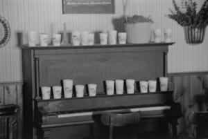Primary view of object titled '[Cups on a piano at the home of Willard Watson, "The Texas Kid", 2]'.