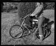 Primary view of [Child on a bicycle in front of a bush]