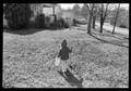 Photograph: [Child in a coat running through a yard]
