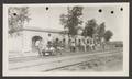 Photograph: [Men standing along train tracks, on a cart and near a fence]
