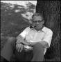 Photograph: [Dr. Wayne Adams  sits beneath a tree]