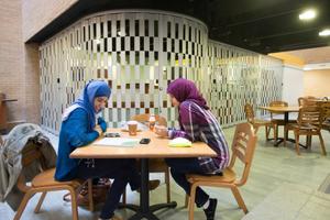 Primary view of object titled '[Two students at GAB Coffee Shop]'.