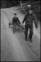 Photograph: [Photograph of a boy pulling another one in a wagon]