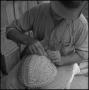 Photograph: [Photograph of a man adjusting a basket weave]