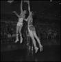 Photograph: [Two basketball players jump, reaching for the hoop]