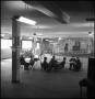 Photograph: [People sitting at tables in a mostly empty room]
