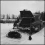Photograph: [Man changing his tire in the snow]
