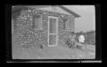 Photograph: [Irene Williams outside of a house with three children]