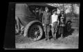 Photograph: [Irene Williams standing in front of the family car with her sons]