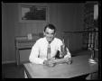 Photograph: [Harvard Bailes Sitting at a Table in KVLB radio station]