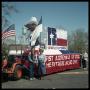Photograph: [Two People by Texas Sesquicentennial Parade Float]