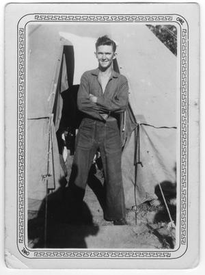 Primary view of object titled '[Connie McCann stands in front of his tent]'.