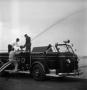 Photograph: [Three Men Spraying Fire Hose on Baton Rouge Fire Department Truck]