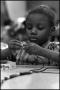 Photograph: [Young Girl Builds a String of Beads]