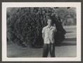 Photograph: [Man Standing in Front of a Bush]