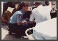 Photograph: [Paramedic and Firefighter Kneel Behind Firetruck]