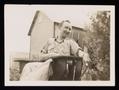 Photograph: [Photograph of Alex Bradford Sitting in a Wooden Patio Chair]