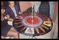 Photograph: [Six People Around a Circular Table With African Art]